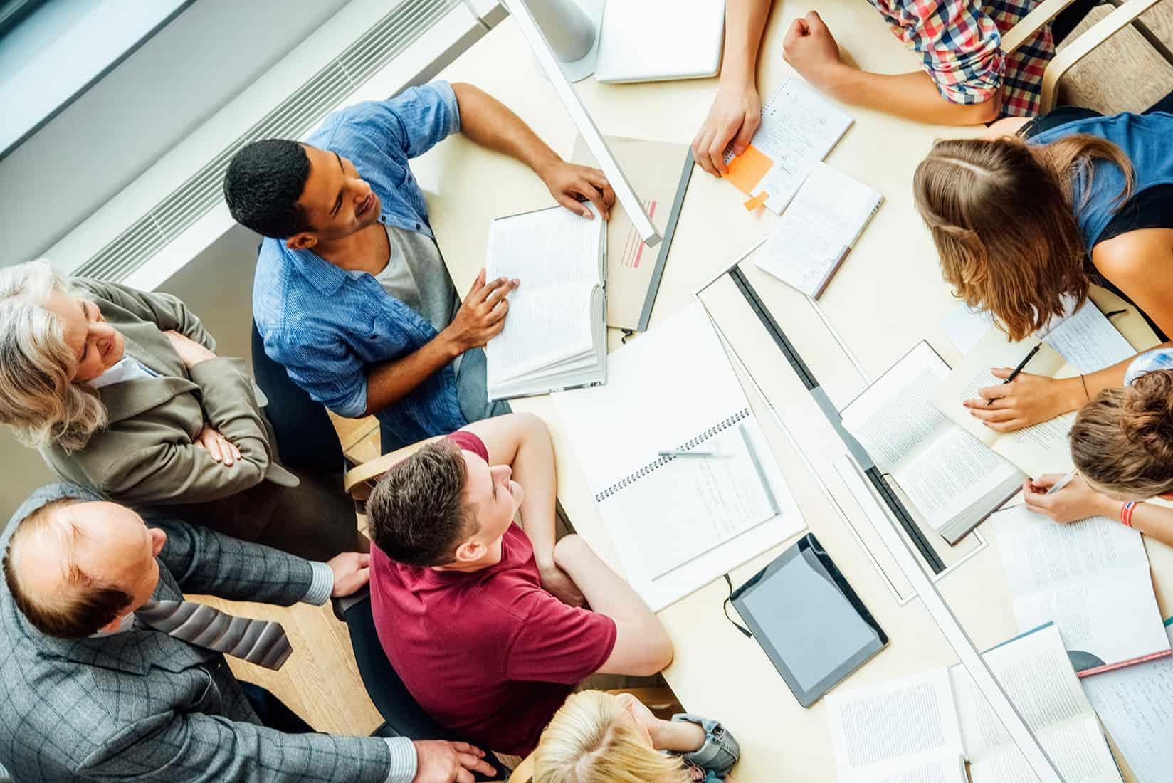 High angle view of professors and university students discussing at table in classroom