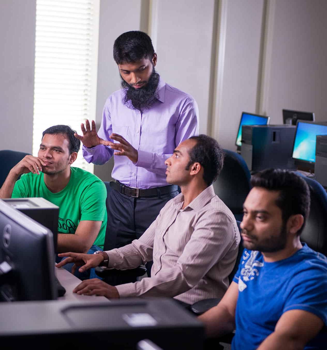 Professor helping three students at computers